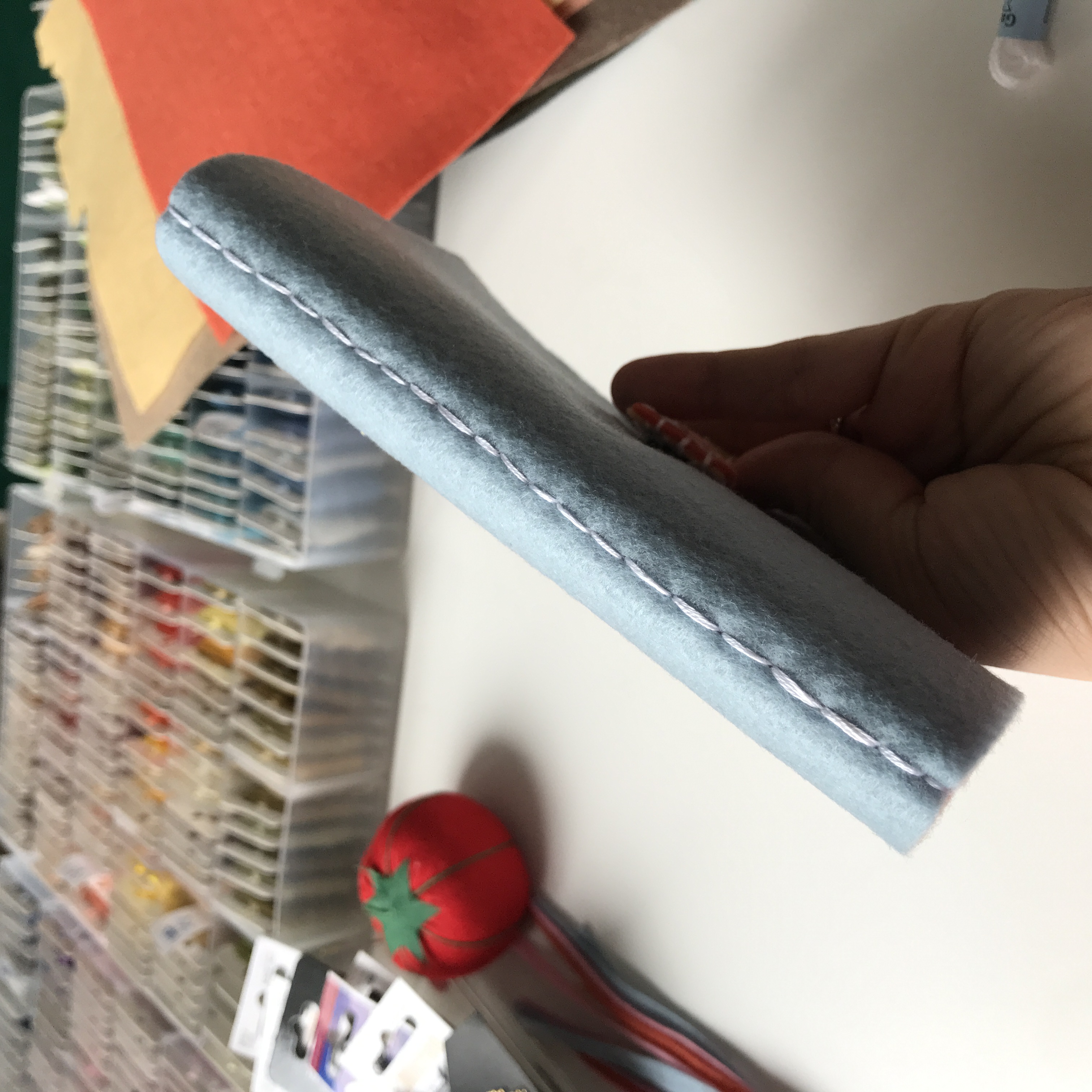 Close-up of pale blue fabric edge with white topstitching, held in hand