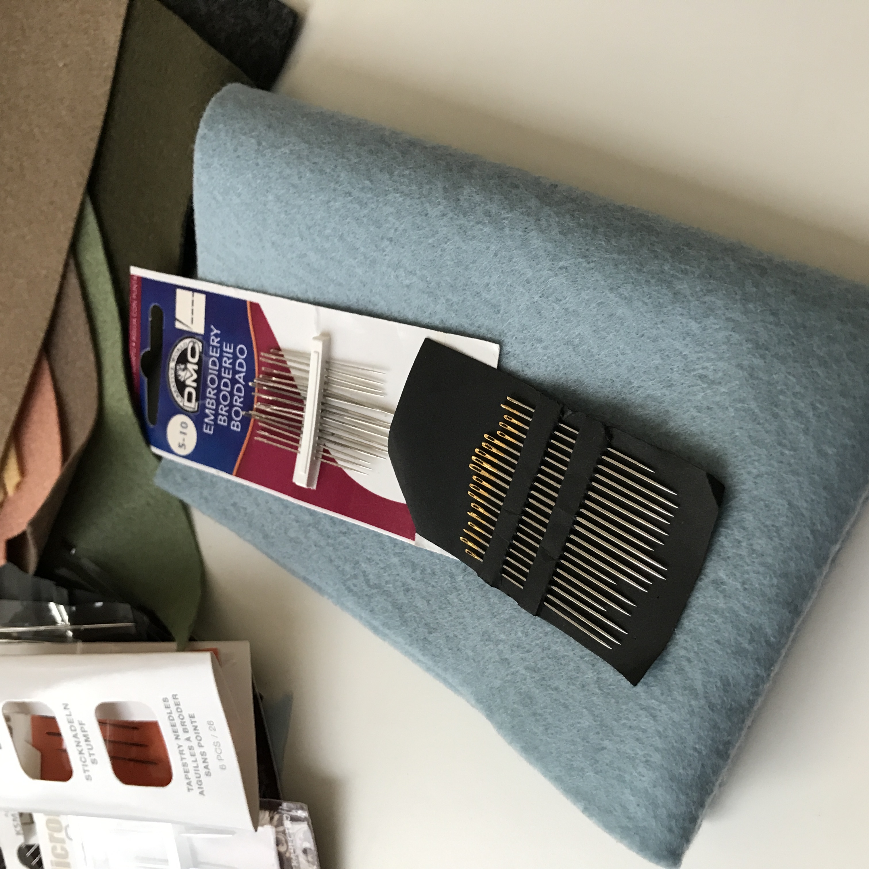 DMC embroidery needle set and set with assorted needles on blue felt background