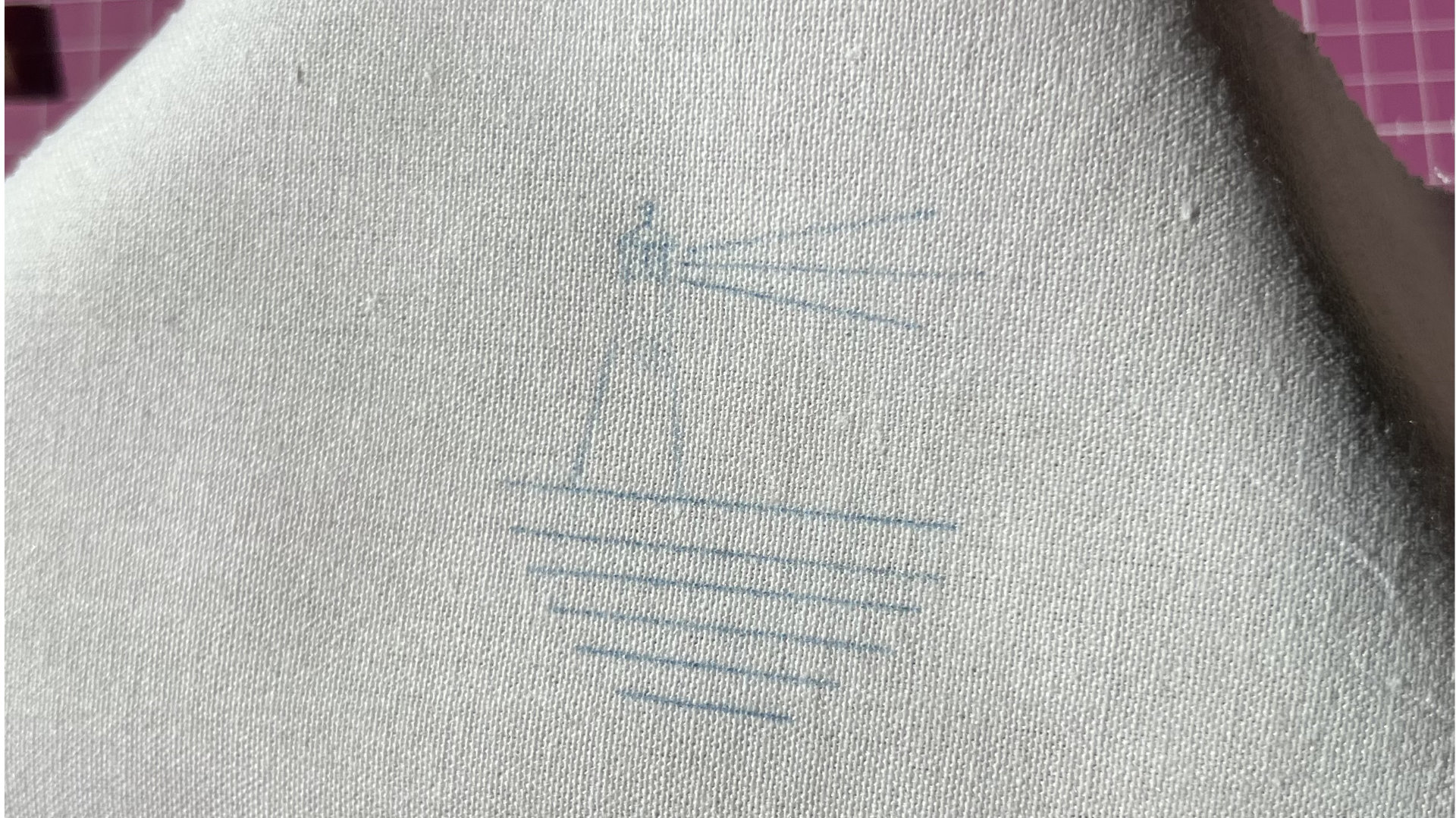 White fabric with pale blue guide lines drawn on the surface.